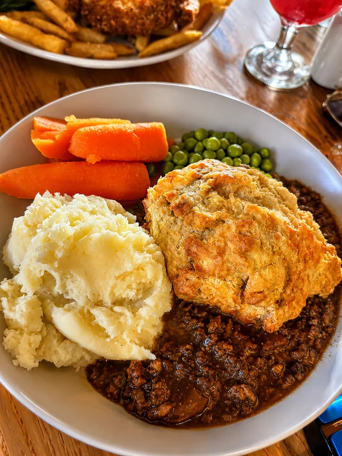 Rich minced beef with a golden dumpling, creamy mash, carrots and peas at The Lakeside Inn