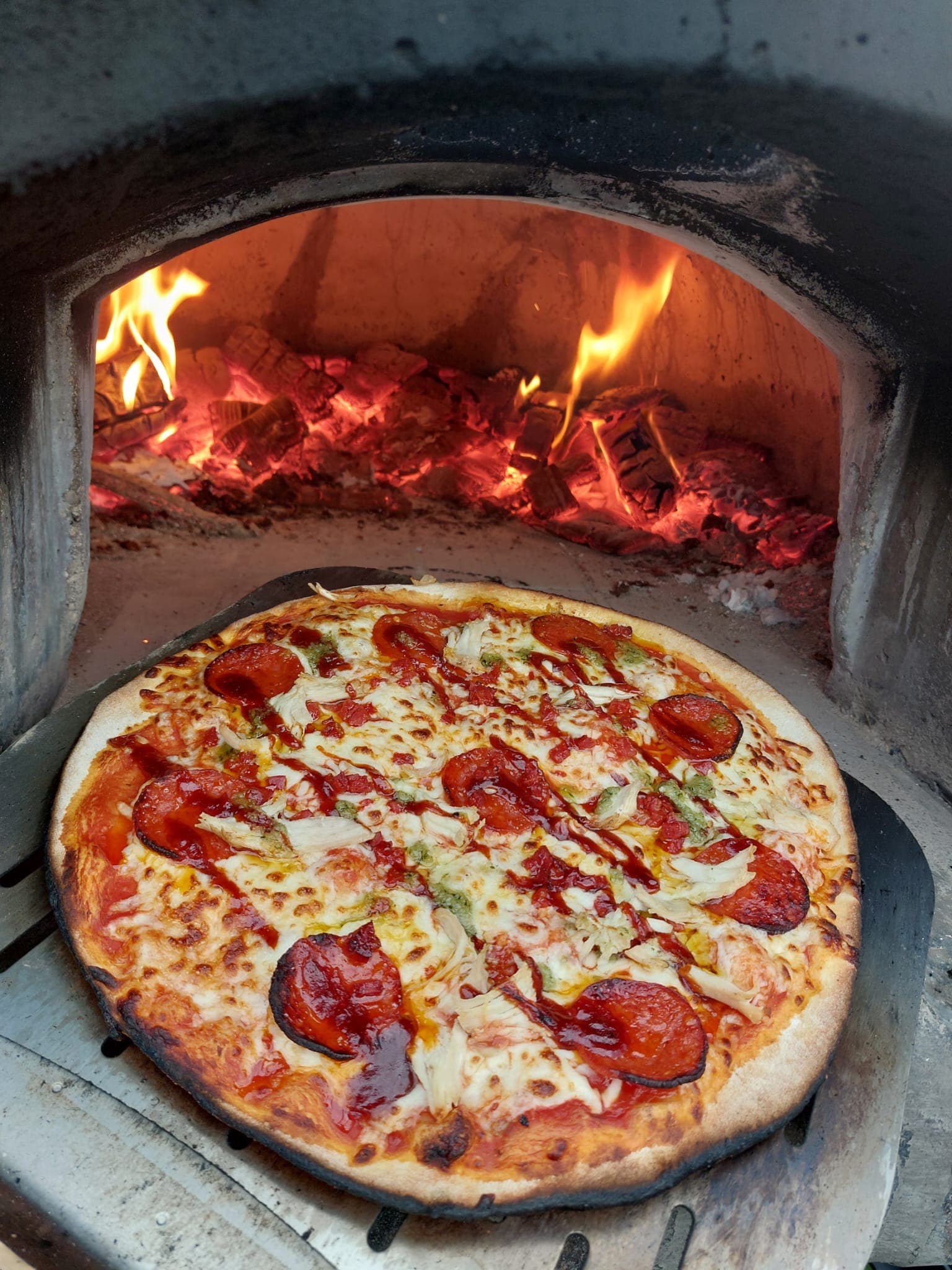 A wood-fired pizza baking in the outdoor oven at The Lakeside