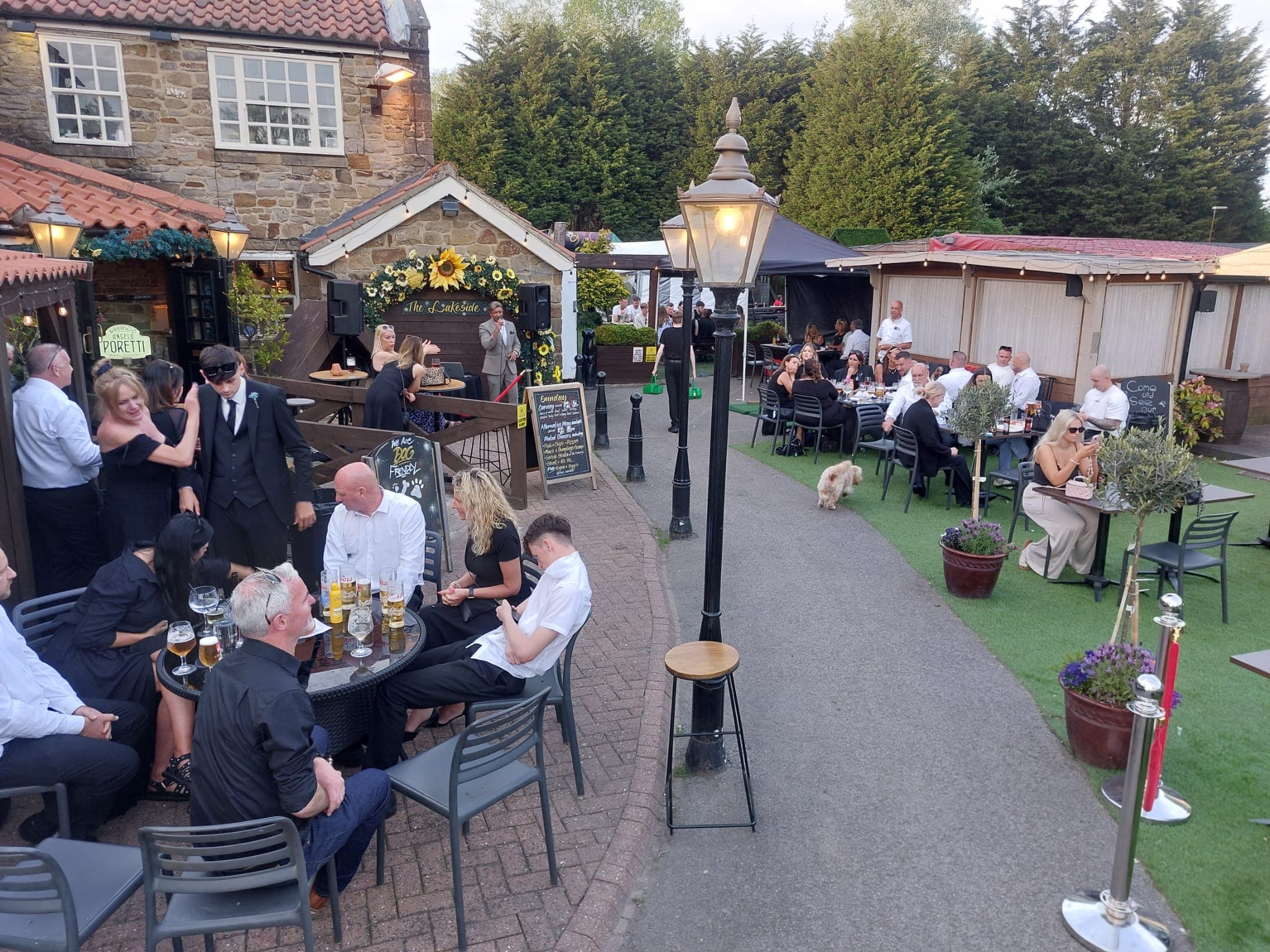 Guests dining and drinking in the garden terrace at The Lakeside on a summer evening